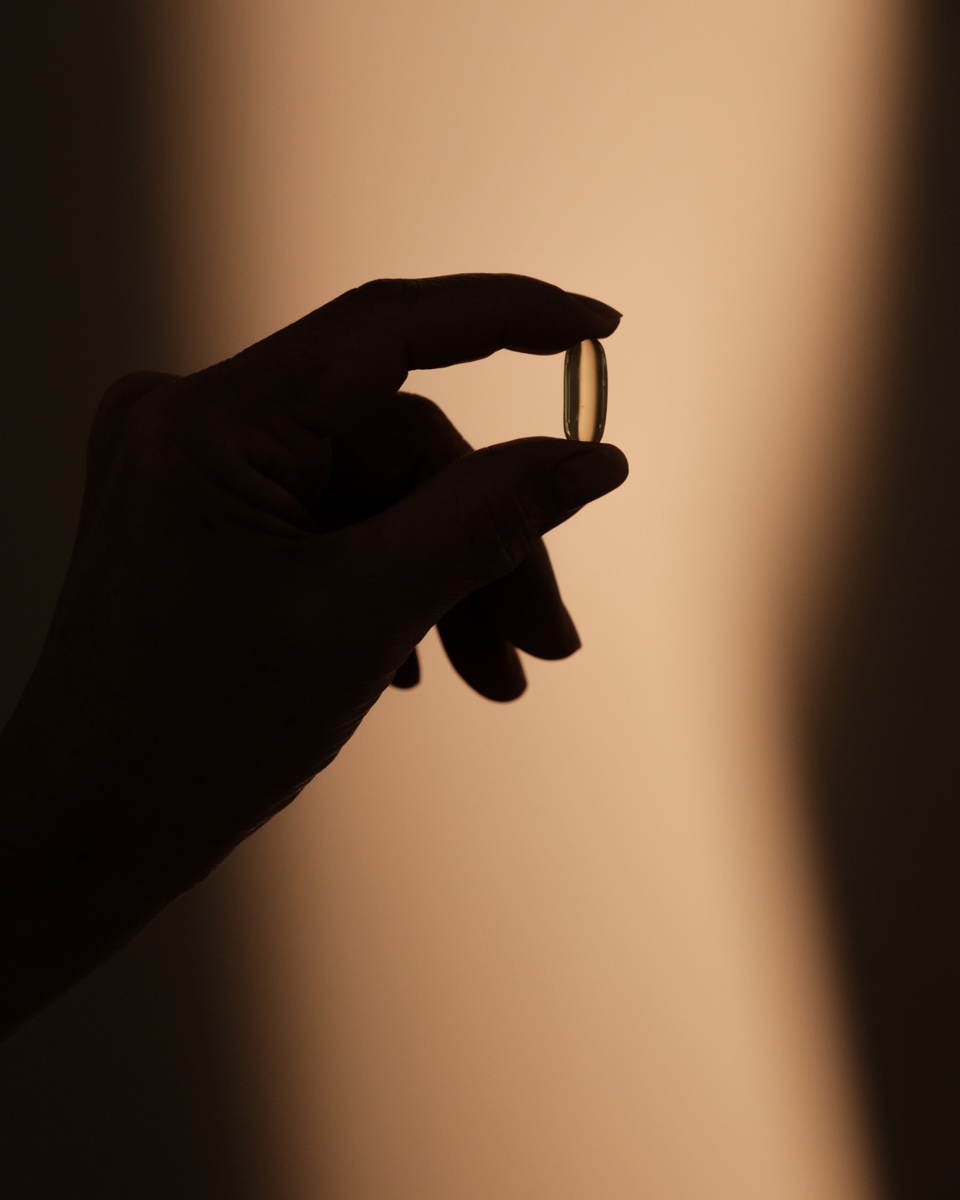 Hand holding a supplement capsule